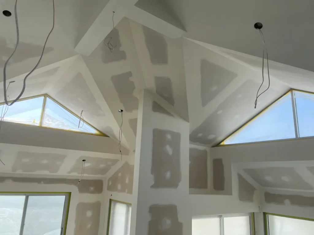 Interior ceiling and walls prepared with plasterboard and joint compound for painting.